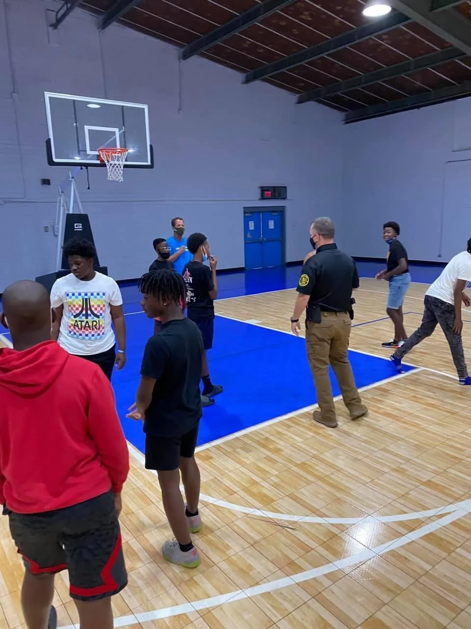 Officers engage with teens in the basketball gym and have a conversation.