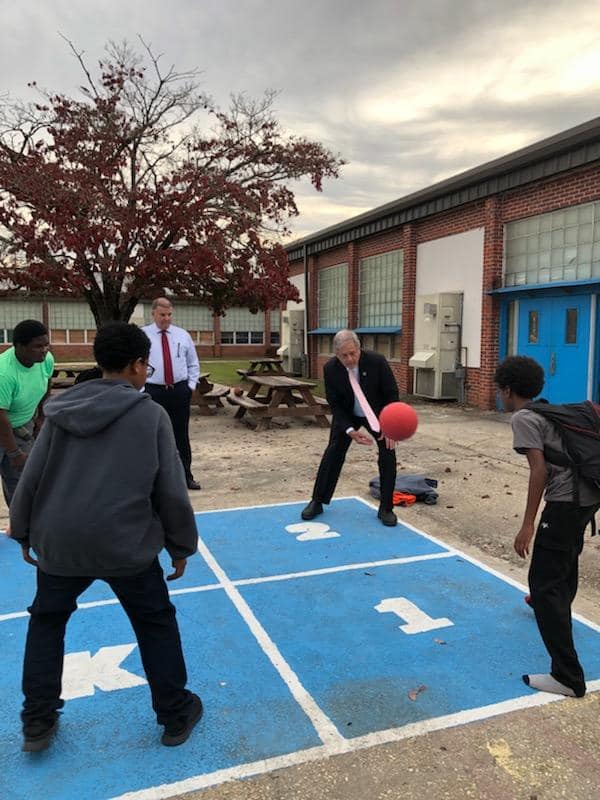 Students in the program are playing basketball with 2 male leaders